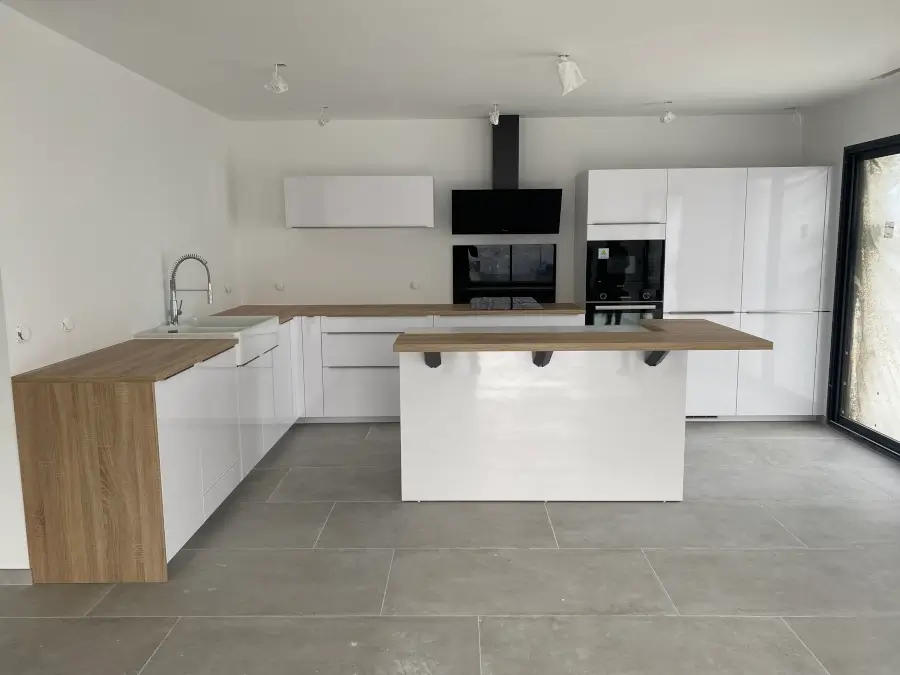 Cuisine sur mesure blanche stratifiée avec un plan de travail en bois clair, offrant une esthétique lumineuse et chaleureuse. Le contraste entre le blanc éclatant et le bois clair crée une atmosphère moderne et accueillante.