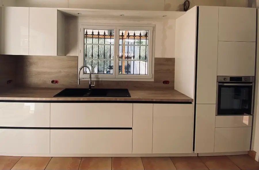Cuisine sur mesure avec un liseré noir, agencée le long d'un seul côté du mur. Cette conception astucieuse optimise l'espace disponible tout en offrant une esthétique moderne et élégante par L. Cuisine et Aménagement sur Nîmes et Montpellier