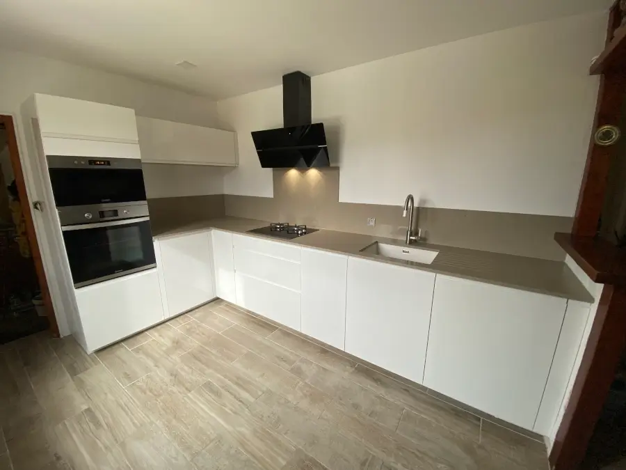 Cuisine sur mesure blanche avec un plan de travail couleur pierre, offrant une esthétique élégante et naturelle. Le contraste entre le blanc éclatant et la couleur pierre crée une ambiance moderne et raffinée par L. Cuisine et Aménagement sur Nîmes et Montpellier.