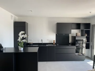 Cuisine sur mesure intégralement noire, créant une ambiance moderne et audacieuse. Le design monochrome apporte une esthétique élégante et minimaliste à l'espace, mettant en valeur le contraste et la simplicité des lignes par L. Cuisines et Aménagement.